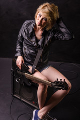 Beautiful blonde dressed in leather jacket with electric guitar