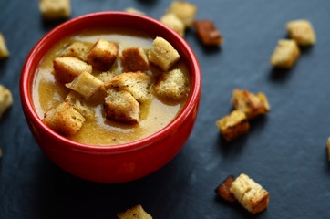 Pumpkin soup with homemade croutons in a small, red bowl