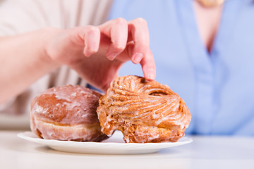 Hand reaches for the sweet donuts on the table
