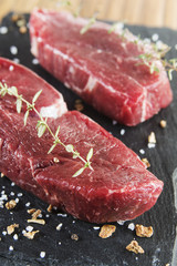 Raw beef tenderloin with spices over a blackboard