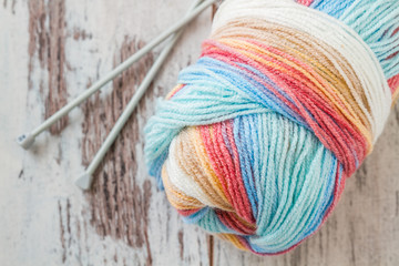 Soft woolen yarn and knitting needles on wooden background