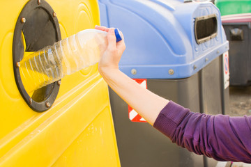 throwing a plastic bottle to recycle container
