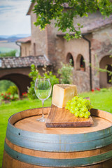 Cheese and grapes on a barrel in the Tuscan landscape Italy