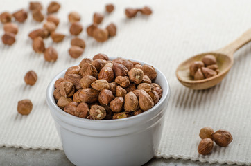 Hazelnuts in a bowl, spoon on the towel