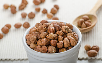 Hazelnuts in a bowl, spoon on the towel