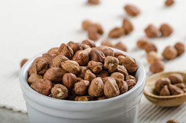 Hazelnuts in a bowl, spoon on the towel