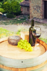 Red wine, pecorino cheese on a wooden barrel in the background o