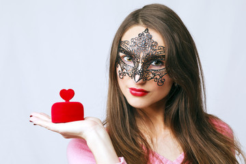 Young woman wearing a venetian mask with a heart shaped gift