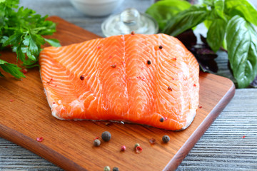 Red fish fillet with greens on a cutting board