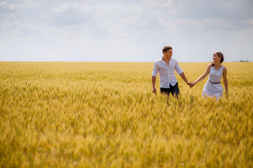 Naklejka na ściany i meble series. a love story. couple runs in the wheat field and smiling