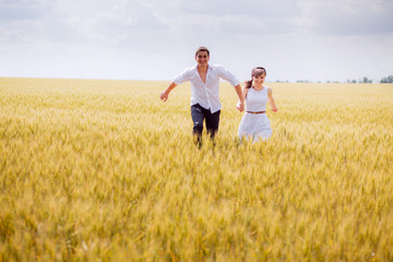 Naklejka premium series. a love story. couple runs in the wheat field and smiling