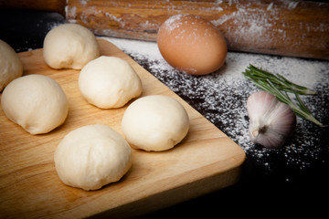 dough on a board with flour. olive oil, eggs, rolling pin, garli