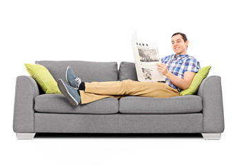 Fototapeta na wymiar Young happy man reading the news on a sofa
