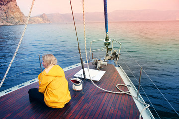young pretty woman on a yacht at sea in a yellow jacket