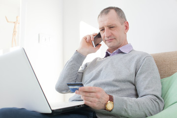 Adult man reading a credit card number during phone call