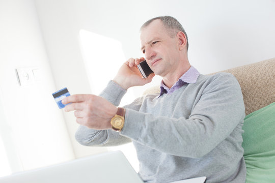 Adult Man Reading A Credit Card Number During Phone Call