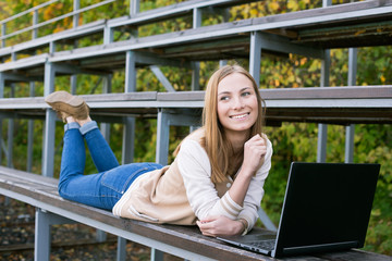 Student lying on sport tribune smiling and looking away