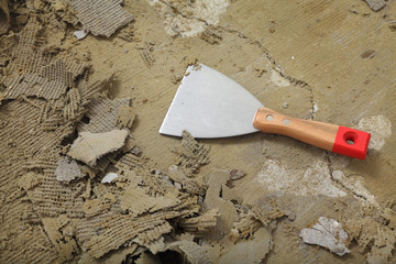 Closeup of putty knife tool at dirty floor