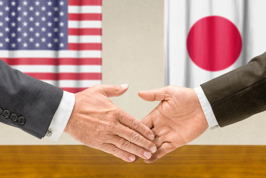 Vertreter der USA und Japans reichen sich die Hand