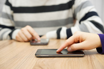 Fototapeta premium man and woman are using a smart phone on wooden desk