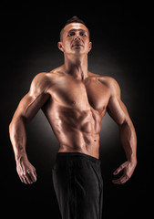 Fototapeta na wymiar Muscular man in studio on dark background