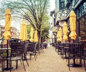 Tables, chairs and umbrellas set up for urban alfresco cafe restaurant sidewalk dining St Louis...