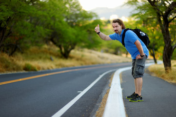Young tourist hitchhiking along a road