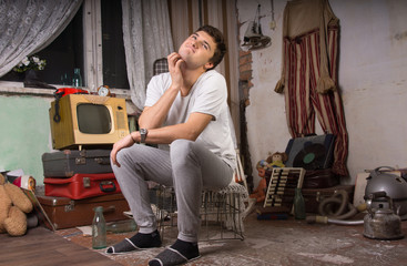 Sitting Man Scratching his Neck at Junk Room