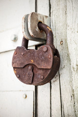 Big old rusted padlock hanging on rural door