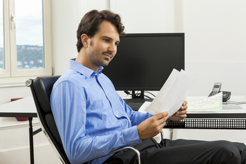 Young handsome man sitting at his desk in the office