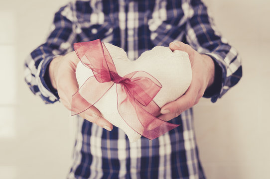 Man in plaid shirt holding a fabric heart with a red ribbon