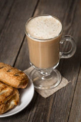 Coffee cup with fresh baked apple pies on wooden surface