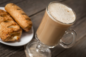 Warm apple pies with cup of coffee on wooden table.