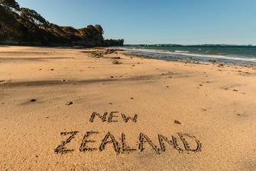 New Zealand written in sand on beach