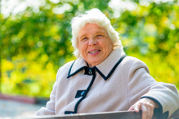 portrait of happy pensioner sitting on a bench in the park