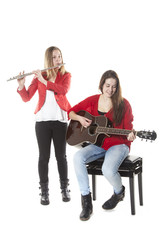 two teenage sisters play flute and guitar in studio