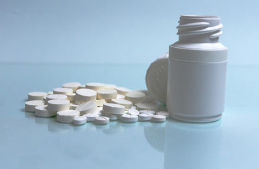 many different size white pills and white pill container