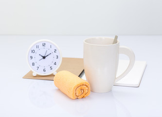 Coffee cup and orange roll cake with office accessories backgrou