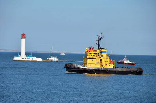 Tugboat in harbor quayside, over lighthouse in Odessa, Ukraine