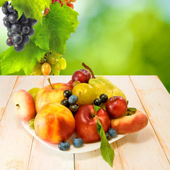 various fresh fruits on a plate on a green background