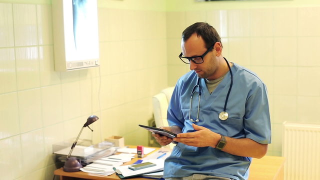 Young doctor with tablet computer sitting on in hospital