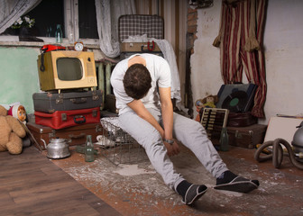 Sleeping Man Sitting on Cage at Junk Room