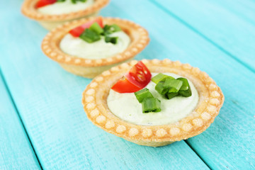 Tartlets with greens and vegetables with sauce on table