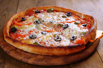 Pizza with cheese on board and wooden table background