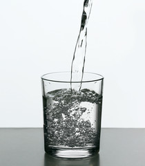 Pouring water from bottle on  glass isolated on white