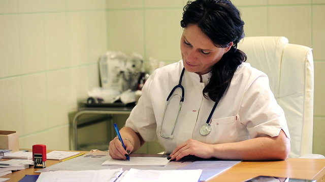 Female doctor writing rx prescription in hospital