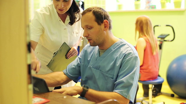 Doctors talking over tablet in rehabilitation room
