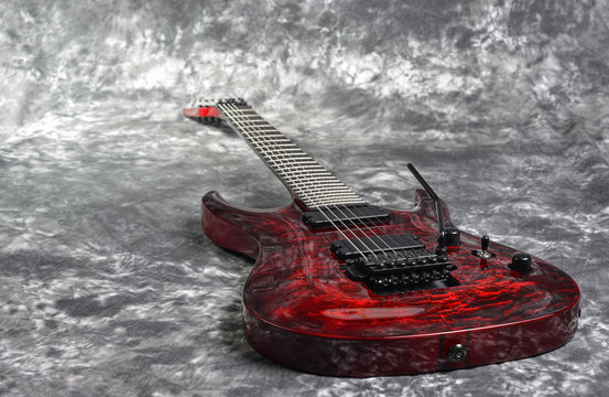 red seven-stringed electric guitar  on white-gray background