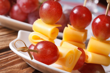grapes and cheese on skewers macro on a plate. horizontal