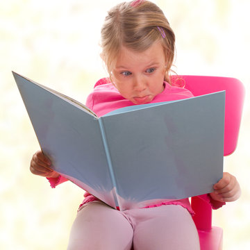Kind mit einem fragendem Blick beim Buchlesen - isoliert